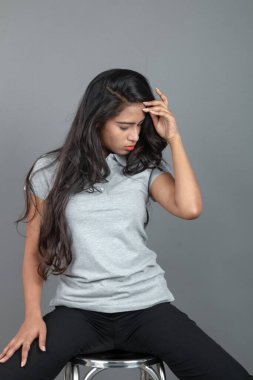 Gündelik iş kıyafetleri giymiş kendine güvenen bir kadın stüdyo ortamında modern bir taburede oturuyor, profesyonelliği, zarafeti ve moda veya iş temalı projeler için uygun duruşu çağrıştırıyor..