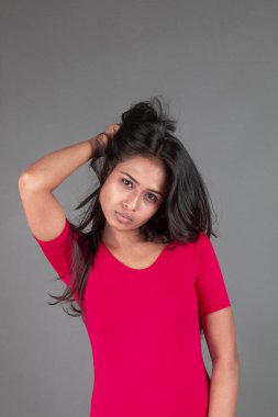 Kırmızı tişörtlü ve siyah taytlı sağlıklı bir kadın yoga yapıyor ve farklı yüz ifadeleriyle esneme egzersizleri yapıyor, gri arka planda izole edilmiş.