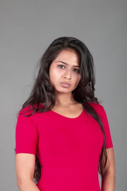 Kırmızı tişörtlü ve siyah taytlı sağlıklı bir kadın yoga yapıyor ve farklı yüz ifadeleriyle esneme egzersizleri yapıyor, gri arka planda izole edilmiş.