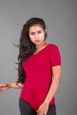 Kırmızı tişörtlü ve siyah taytlı sağlıklı bir kadın yoga yapıyor ve farklı yüz ifadeleriyle esneme egzersizleri yapıyor, gri arka planda izole edilmiş.