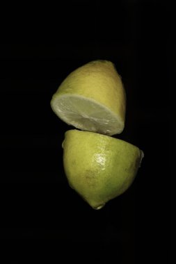 Sarı limon dilimleri siyah arka plan makrosu üzerinde izole edilmiş.