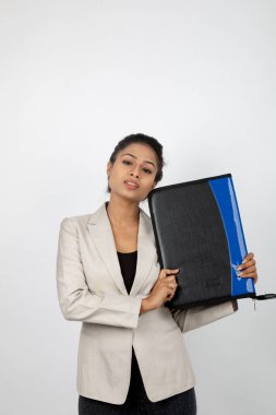 Ofisteki kadın bir dosya tutuyor ve sunum yapıyor. Resmi giyinmiş genç bir kadın beyaz ceket giyiyor ve elinde floder ile farklı ifadeler takınıyor.