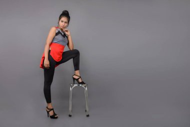 Genç, güzel bir Hintli kadın modelin gündelik kıyafetleriyle stüdyo fotoğrafı. Kırmızı ve gri tasarımcı bluzu ve beyaz arka planda siyah kot pantolon giyiyor. Kadın manken. Moda Portresi.