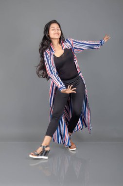 Siyah tayt giyen güzel, genç bir Hintli kadın, siyah üst ve kırmızı, mavi, beyaz çizgili tunik. Bir stüdyoda kutlama yapmak için gülüyor, dönüyor, zıplıyor ve dans ediyor.