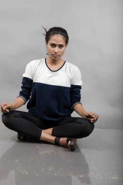 Gri arka planda günlük kışlık giysili Hintli genç bayan model. Siyah tayt giyen uzun siyah saçlı bir manken, mavi beyaz bir kazak..