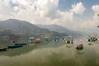 Pokhara, Nepal 'de sisli bir sabahta Phewa gölünde yüzen teknelerin güzel manzarası..