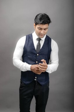 Gri arka planda resmi giyinmiş neşeli, genç ve yakışıklı Hintli iş adamının stüdyo çekimi. Erkek model. Moda Portresi.