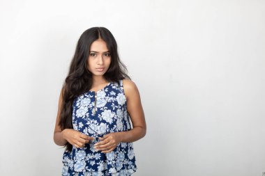 Genç ve güzel bir Hintli kadın modelin atölye fotoğrafı. Mavi ve beyaz bir bluz, mavi kot pantolon ve beyaz arka planda temiz bir gözlük giyiyor. Kadın manken. Moda Portresi.