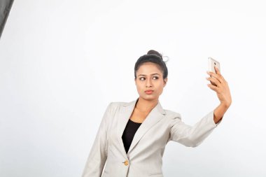 Kurumsal ofis hanımı, siyah saçlı, kalemle oynaşan, resmi olarak akıllı telefonlu beyaz ceketli beyaz arka planlı bir kadın..