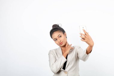 Kurumsal ofis hanımı, siyah saçlı, kalemle oynaşan, resmi olarak akıllı telefonlu beyaz ceketli beyaz arka planlı bir kadın..