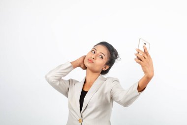 Kurumsal ofis hanımı, siyah saçlı, kalemle oynaşan, resmi olarak akıllı telefonlu beyaz ceketli beyaz arka planlı bir kadın..