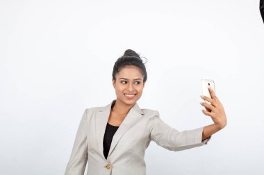 Kurumsal ofis hanımı, siyah saçlı, kalemle oynaşan, resmi olarak akıllı telefonlu beyaz ceketli beyaz arka planlı bir kadın..