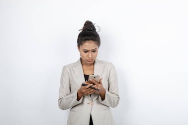 Kurumsal ofis hanımı, siyah saçlı, kalemle oynaşan, resmi olarak akıllı telefonlu beyaz ceketli beyaz arka planlı bir kadın..