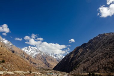 Dağların manzarası. Mavi gökyüzü ile kaplı kar manzarası, Kaşmir 'deki dağların yamaçlarında ağaçlarla kaplı beyaz bulut.