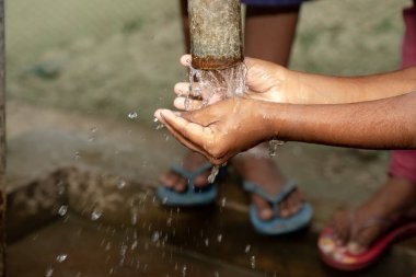 Çocuklar açık su musluğunda ellerini yıkıyorlar. Ellerini temiz tut. Mevcut durum 2020. Covid19 Ellerinizi yıkayın kampanyası.