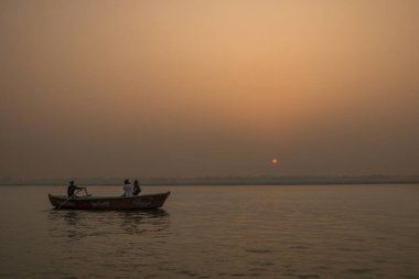 Huzurlu bir gün doğumu, gün batımı sıcak nehir manzarası ve teknelerde insanlar. Ganga nehir kıyısı. Varanasi, Hindistan.