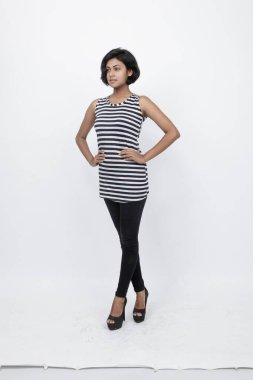 Siyah-beyaz çizgili kolsuz bluz, siyah kot, beyaz arka planda yüksek topuklu, moda, güzellik, kendine güven için ideal, minimal stil..