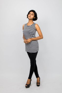 Siyah-beyaz çizgili kolsuz bluz, siyah kot, beyaz arka planda yüksek topuklu, moda, güzellik, kendine güven için ideal, minimal stil..