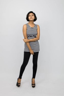 Siyah-beyaz çizgili kolsuz bluz, siyah kot, beyaz arka planda yüksek topuklu, moda, güzellik, kendine güven için ideal, minimal stil..