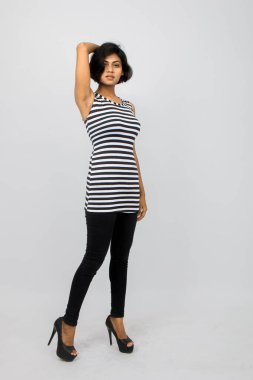 Siyah-beyaz çizgili kolsuz bluz, siyah kot, beyaz arka planda yüksek topuklu, moda, güzellik, kendine güven için ideal, minimal stil..