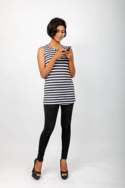 Siyah-beyaz çizgili kolsuz bluz, siyah kot, beyaz arka planda yüksek topuklu, moda, güzellik, kendine güven için ideal, minimal stil..