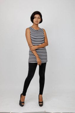 Siyah-beyaz çizgili kolsuz bluz, siyah kot, beyaz arka planda yüksek topuklu, moda, güzellik, kendine güven için ideal, minimal stil..