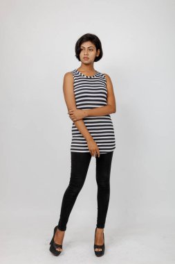 Siyah-beyaz çizgili kolsuz bluz, siyah kot, beyaz arka planda yüksek topuklu, moda, güzellik, kendine güven için ideal, minimal stil..