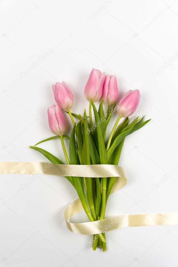 Tenderly pink tulips with ribbon on a white background. Top view. Vertical photo. Valentine's Day. Easter. Mother's day. Spring flowers