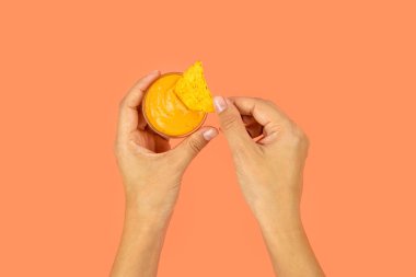 Kadının elleri peynir sosu ve çıtır çıtır cipslerle renkli bir fotoğraf tutuyor..