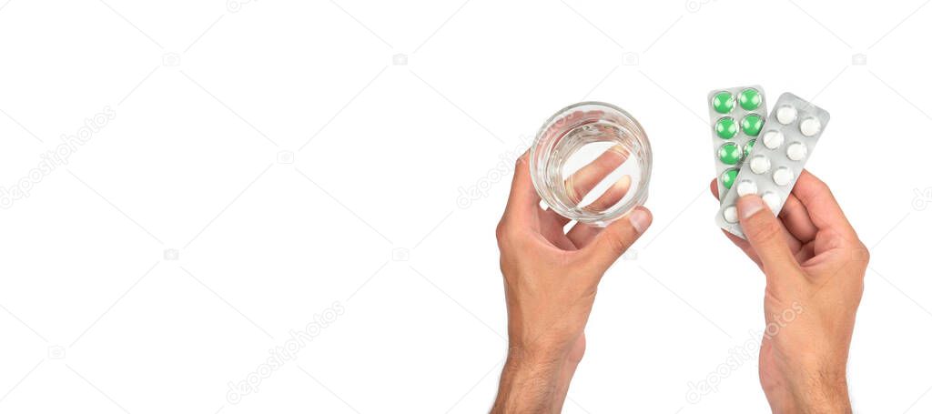 Male hands are holding packs of pills and a glass of water on a white banner. Medicine and treatment concept. Top view.