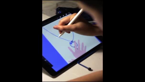 La niña dibuja una ilustración en una tableta gráfica en la noche bajo la luz de una lámpara. — Vídeos de Stock