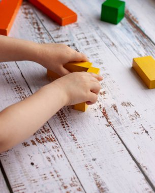 Beyaz ahşap arka planda tahta bloklar çalan bir çocuğun elleri.