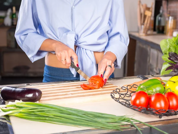 Женщина режет помидоры на кухне Стоковое Изображение