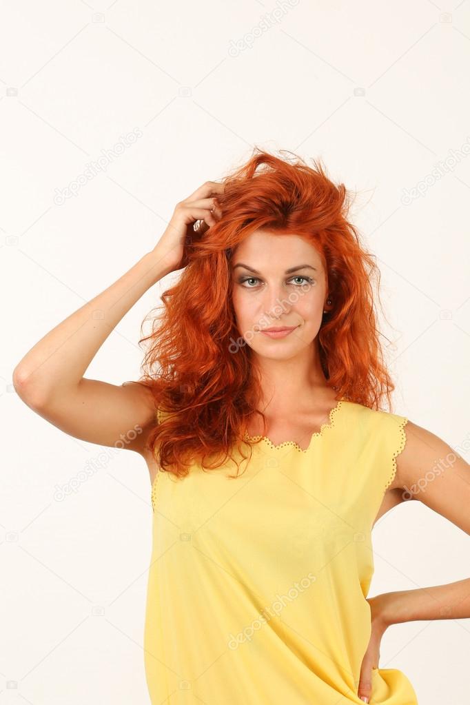 portrait of smirking redhead young woman in yellow dress