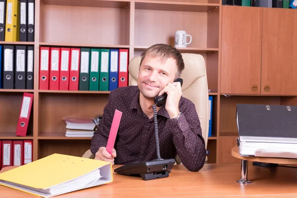 Улыбающийся человек в офисе разговаривает по телефону — стоковое фото