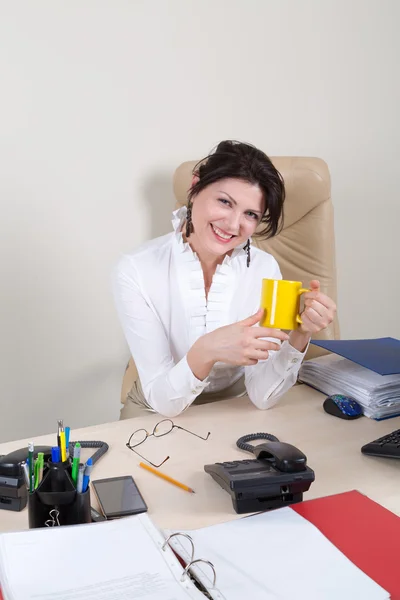 Usmívající se žena v úřadu s žlutým cup — Stock fotografie