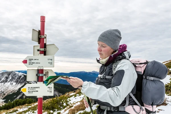 Mujer buscando el camino correcto en el mapa en las montañas — Foto de Stock