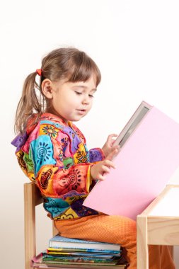 küçük çocuk kız okuma kitap yığılmış kitaplar üzerinde oturan