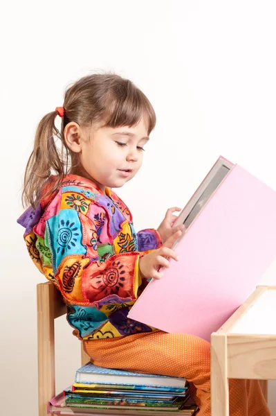 Small kid girl reading book sitting on stacked books Stock Picture