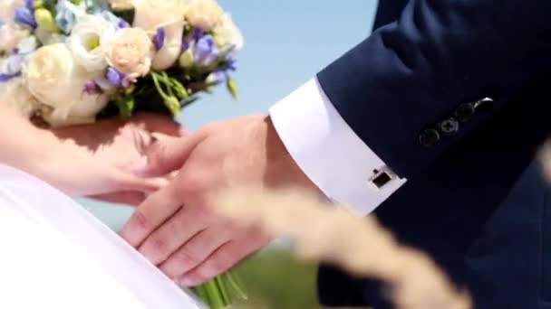 Крупный план рук жениха и невесты с букетом — стоковое видео