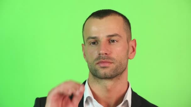 Een man op een groene achtergrond close-up — Stockvideo