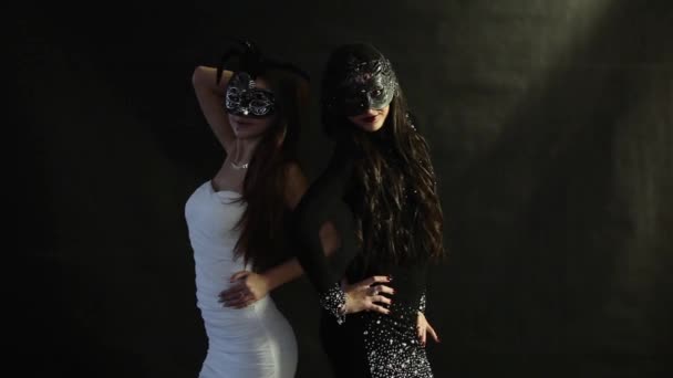 Dos chicas con máscaras posando sobre un fondo negro — Vídeos de Stock