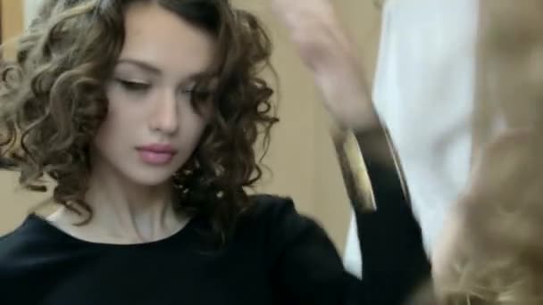 Mooie curly brunette kijkt in de spiegel — Stockvideo