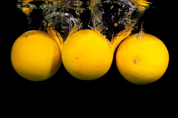 Citrusfrugter falder i vandet - Stock-foto