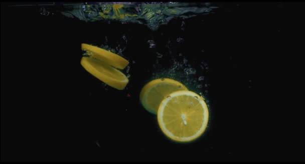 Jeruk jatuh ke dalam air dalam gerakan lambat pada latar belakang hitam — Stok Video