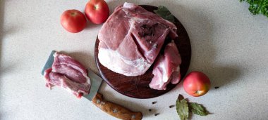 Hafif bir arka planda, çiğ et, içinde domates ve baharatlar olan ahşap bir tahtanın üzerinde yatıyor.