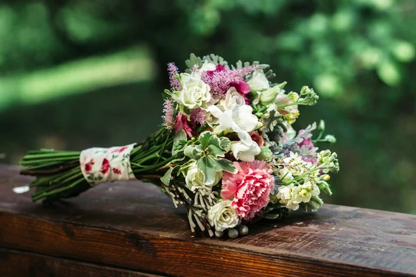 Wedding bouquet of carnations and roses, on a wooden table — Stock Photo, Image