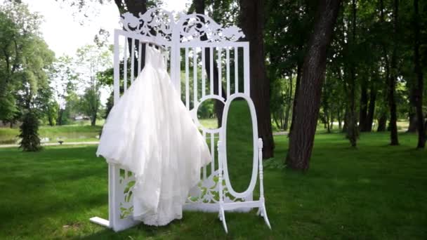 Весільна сукня висить в красивому саду . — стокове відео