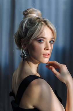 Siyah bluzlu güzel bir sarışının stüdyo portresini kapat ve kameraya bak..