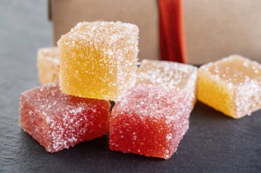 Küplere kesilmiş leziz renkli marmelatlar. Siyah tahtada yatıyor.